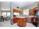 Well-lit kitchen with wood cabinets, center island, stainless appliances, and a view to the living area at 1308 Crystal Greens Dr, Sun City Center, FL 33573