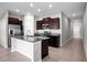 Spacious kitchen with dark wood cabinetry, granite countertops, stainless steel appliances, and an island with a sink at 13355 Willow Bluestar Loop, Riverview, FL 33579