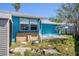 Exterior of the home with bright blue siding and an overgrown backyard at 14040 Miramar Ave, Madeira Beach, FL 33708
