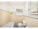 Bathroom with yellow tile, tub, toilet, and window letting in natural light at 14040 Miramar Ave, Madeira Beach, FL 33708