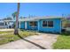 Inviting one-story home painted blue, accented by a tidy lawn and a clear blue sky at 14040 Miramar Ave, Madeira Beach, FL 33708