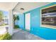 Blue painted exterior entrance with white door, stone column and green landscaped bushes at 14040 Miramar Ave, Madeira Beach, FL 33708