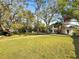 Expansive front yard featuring lush lawn and mature trees leading to a charming two story home with a red tile roof at 2632 S Dundee St, Tampa, FL 33629