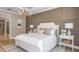 Serene main bedroom with a decorative accent wall, white furniture, and elegant lighting fixtures at 34088 Anchor Light Ln, Wesley Chapel, FL 33543