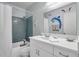 Bathroom with light-blue tiling in shower, white vanity and toilet, and a decorative mirror with whimsical dolphin design at 4766 Snook Se Dr, St Petersburg, FL 33705