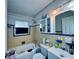 Compact bathroom with blue and beige tiling, a bathtub, toilet, and sink at 619 41St Ne Ave, St Petersburg, FL 33703