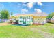 A wide backyard view, showing green grass, mulch beds, and a glass-enclosed porch area at 7041 Daggett Ter, New Port Richey, FL 34655