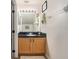 Bathroom with natural wood vanity and black countertop and large mirror at 7116 Colonial Lake Dr, Riverview, FL 33578