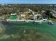 Stunning aerial view of a waterfront estate featuring lush gardens, pool, tennis court, and private dock at 802 Druid S Rd, Clearwater, FL 33756