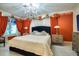 Luxurious bedroom boasts orange accent walls, a stylish chandelier, and an inviting king-size bed at 802 Druid S Rd, Clearwater, FL 33756