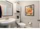 Well-lit bathroom with a pedestal sink, toilet, and colorful art, providing a functional and stylish space at 10106 Corso Milano Dr, Tampa, FL 33625