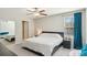 Comfortable bedroom featuring a large bed, ceiling fan, window with blue curtains, and a mirrored closet door at 11944 Miracle Mile Dr, Riverview, FL 33578