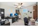 Bright home office featuring a ceiling fan, a window overlooking the neighborhood, and dual monitor setup on a sleek, black desk at 11944 Miracle Mile Dr, Riverview, FL 33578