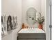 Modern powder room features a gray vanity with a white countertop, a round mirror, and updated fixtures at 11944 Miracle Mile Dr, Riverview, FL 33578