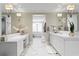 Bright bathroom with double vanities, white marble floors, modern lighting, and a soaking tub in the background at 146 4Th Ne Ave # 600, St Petersburg, FL 33701