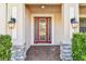 Elegant front door with decorative glass panels, flanked by stone columns and stylish outdoor lighting at 19432 Whispering Brook Dr, Tampa, FL 33647