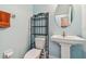 Powder room with a sleek pedestal sink, decorative metal shelving, and an orange towel accent at 19432 Whispering Brook Dr, Tampa, FL 33647