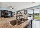 Kitchen island featuring a granite countertop, stainless steel sink, and view of the living area and waterfront at 19432 Whispering Brook Dr, Tampa, FL 33647