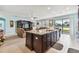 Open-concept kitchen island with granite countertop, dark wood cabinetry, and views of the living room and lake at 19432 Whispering Brook Dr, Tampa, FL 33647