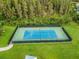 Aerial view showcasing a fenced tennis court with lighting, manicured landscaping and a green common area at 19432 Whispering Brook Dr, Tampa, FL 33647