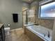 Bathroom showcasing a tiled tub with glass shower and a window for natural light at 2206 Landside Dr, Valrico, FL 33594