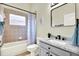 Comfortable bathroom featuring neutral tile, a tub with shower, a modern vanity, and stylish decor at 22647 Eagles Watch Dr, Land O Lakes, FL 34639