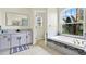 Bright bathroom featuring a soaking tub with a large window view, modern vanity, and neutral tile flooring at 22647 Eagles Watch Dr, Land O Lakes, FL 34639