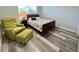 Cozy bedroom features a green chair, side table with lamp, and wood grain flooring at 2348 Shelley St # 8, Clearwater, FL 33765