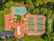 Stunning aerial view of community pool, clubhouse, and tennis courts surrounded by lush greenery and serene pond at 2400 Feather Sound Dr # 1118, Clearwater, FL 33762