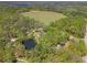 A scenic aerial view featuring a tranquil pond adjacent to a large open field and lush forestry at 26290 Hayman Rd, Brooksville, FL 34602