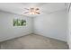 Bedroom features a ceiling fan, natural light from a window, neutral paint, and comfortable carpet at 26290 Hayman Rd, Brooksville, FL 34602