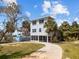 Exterior elevation of home with circular driveway, lush landscaping, and covered patio at 3457 Cyclone Dr, Weeki Wachee, FL 34607