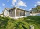 Backyard showcasing the screened-in patio, lush lawn and home's exterior under a partly cloudy sky at 3646 Springfield Dr, Holiday, FL 34691