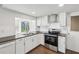 Kitchen featuring white cabinets, stainless steel appliances, and wood-look tile floors at 3646 Springfield Dr, Holiday, FL 34691