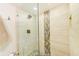 Modern shower featuring glass enclosure, rainfall showerhead, neutral tile and decorative accent tiles at 3820 Gulf Blvd # 802, St Pete Beach, FL 33706