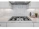 Close-up of a kitchen cooktop, showcasing a white backsplash and modern stainless steel range hood at 4314 Graticola Rd, Wesley Chapel, FL 33543