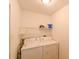 Bright laundry room with appliances, overhead shelving and crisp white walls at 4915 Churchill Pl, Land O Lakes, FL 34639