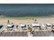Birds-eye view of the beach with white sand, shelters, palm trees, and parking at 5036 Sand Castle Dr, New Port Richey, FL 34652