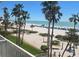 Balcony view showcasing a white sandy beach, clear blue ocean, and tall palm trees under a bright sunny sky at 5500 Gulf Blvd # 4226, St Pete Beach, FL 33706