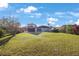 Expansive backyard showcases lush green lawn, in-ground pool, second-story balcony, and tropical landscaping for privacy at 5938 Oakhurst Dr, Seminole, FL 33772