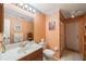 Cozy bathroom featuring a white vanity, toilet, and shower area in a peach-toned setting at 5938 Oakhurst Dr, Seminole, FL 33772