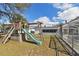 Backyard with playground set, partially fenced-in yard, and a screened patio for outdoor fun at 6712 Runningwoods Dr, Tampa, FL 33634