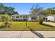 Single-story home with a well-maintained lawn, landscaping and walkway to the entrance of the home at 6712 Runningwoods Dr, Tampa, FL 33634