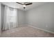 This bedroom features neutral carpet, a ceiling fan and a window with white curtains at 7047 Towne Lake Rd, Riverview, FL 33578