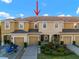 Townhome complex features tan siding, attached garages, and manicured landscaping at 7047 Towne Lake Rd, Riverview, FL 33578