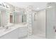 Well-lit bathroom with a shower, white cabinets, sink, and floral wallpaper at 8040 Sailboat Key S Blvd # 402, St Pete Beach, FL 33707