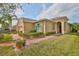 Close-up of tan home with well-manicured lawn, brick walkway and tropical landscaping at 807 Chipper Dr, Sun City Center, FL 33573