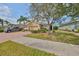 Charming tan home featuring lush landscaping, a brick driveway, and a two-car garage at 807 Chipper Dr, Sun City Center, FL 33573