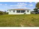 Expansive backyard with verdant grass, patio, and rear view of the home's screened in lanai at 834 Birdie Way, Apollo Beach, FL 33572
