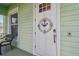 Close-up of the front door with nautical decor, chair, and light green siding at 834 Birdie Way, Apollo Beach, FL 33572